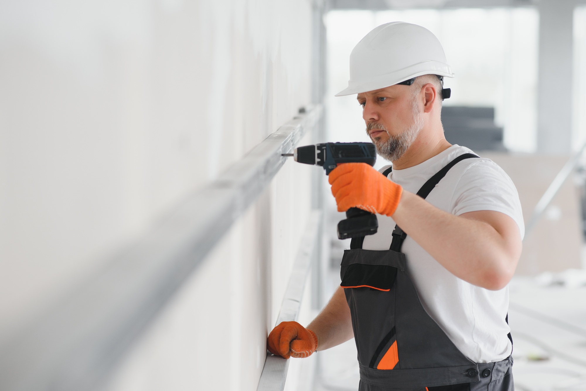 man drywall worker installing plasterboard sheet to wall